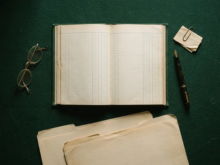Archival folders and reading glasses on an auditor’s desk